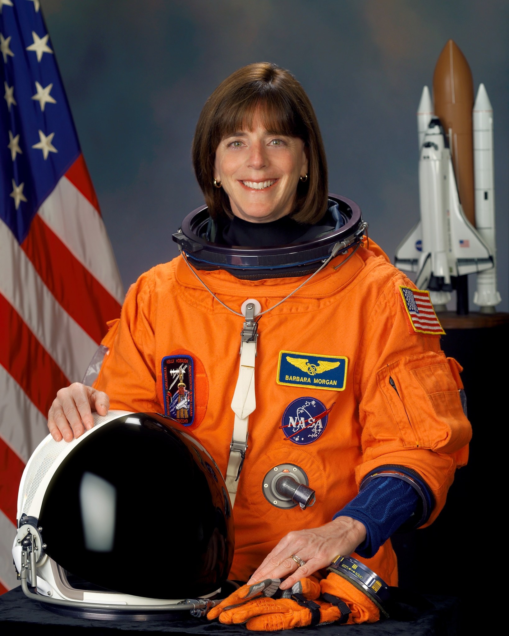 Astronaut Barbara Morgan posing for her official portrait in an orange suit.