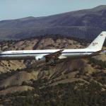 A picture of an airplane flying over some hills.
