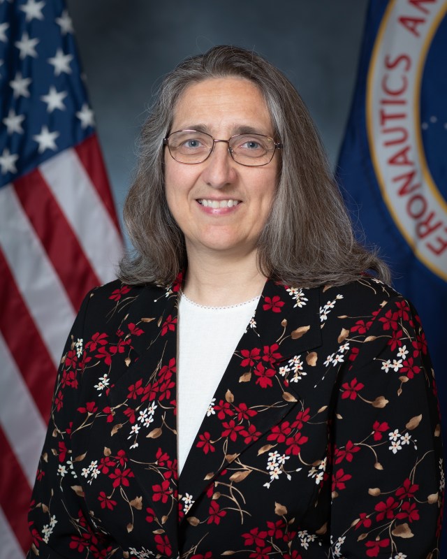 Portrait of Maria Babula with U.S. and NASA flags in background.