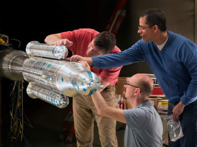 Wind tunnel engineers work on a model of the Space Launch System.