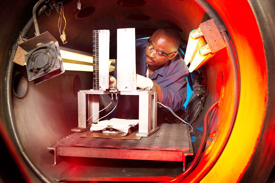 A technician sets up a flammability test in a testing chamber.