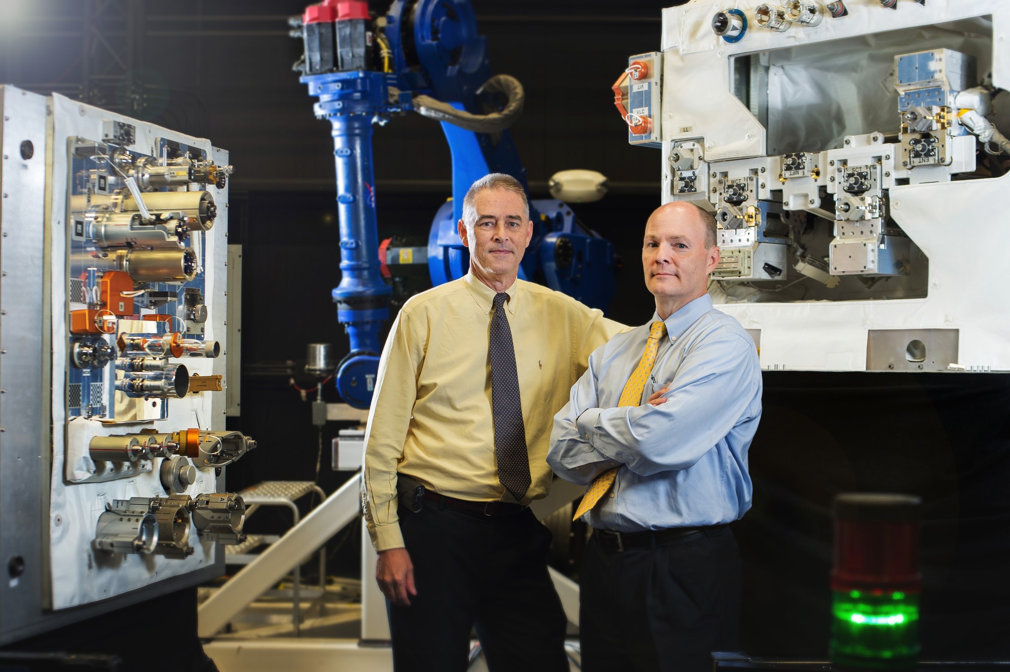 Goddard engineers stand in from of Robotic Refueling Mission mock up