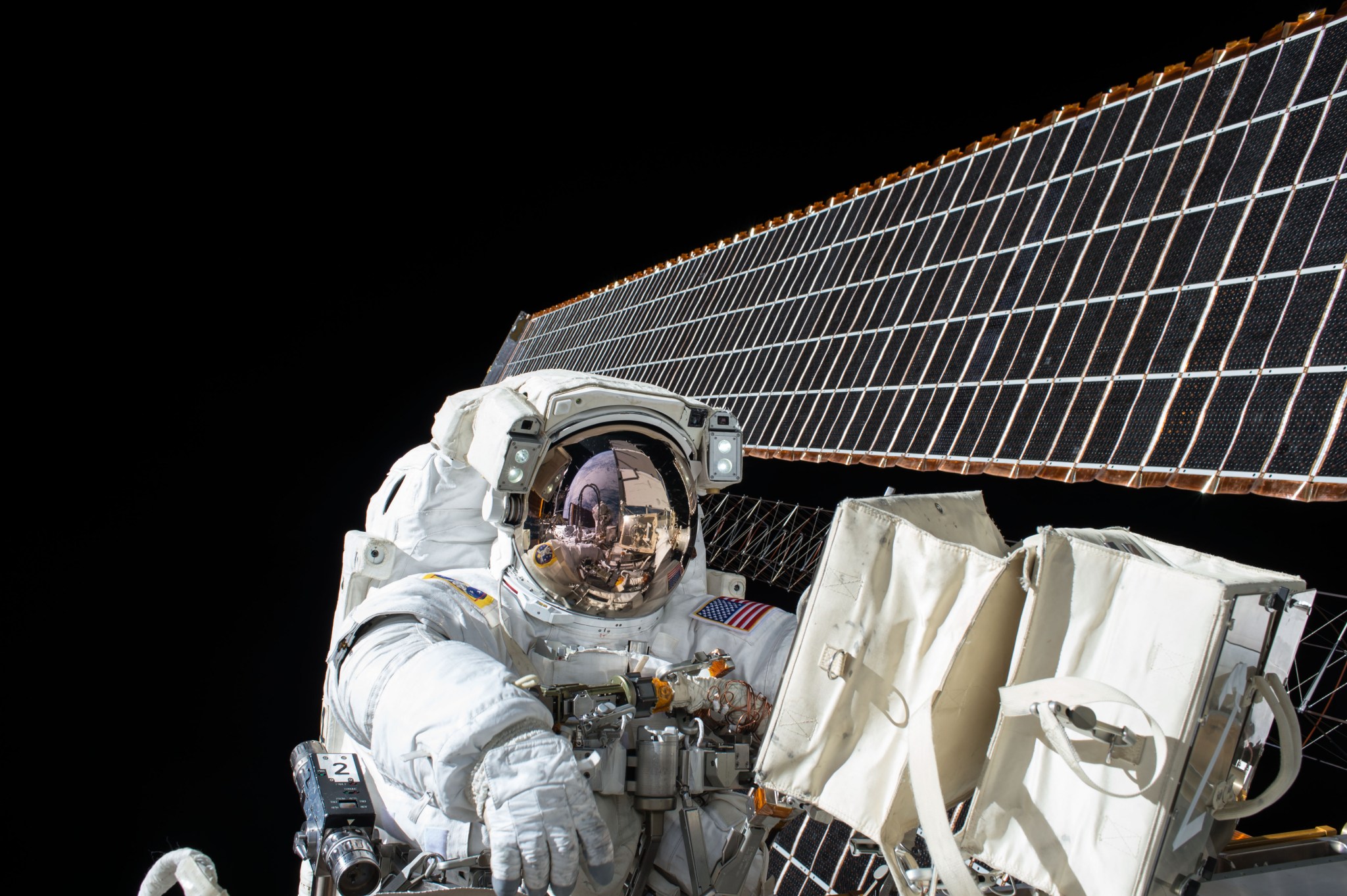 Astronaut in spacesuit outside International Space Station with solar array in background