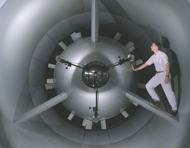 A man inside the 8x6 Supersonic Wind Tunnel getting the vortex generator and bellmouth rake installed.