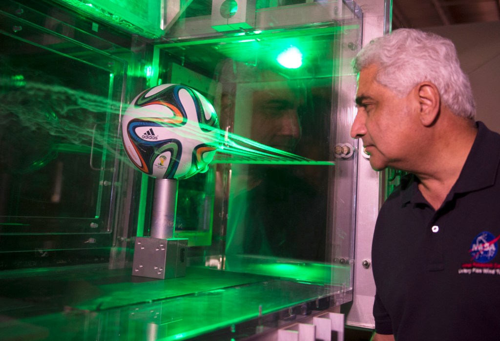 man looking at soccer ball in a water chamber with lasers around it