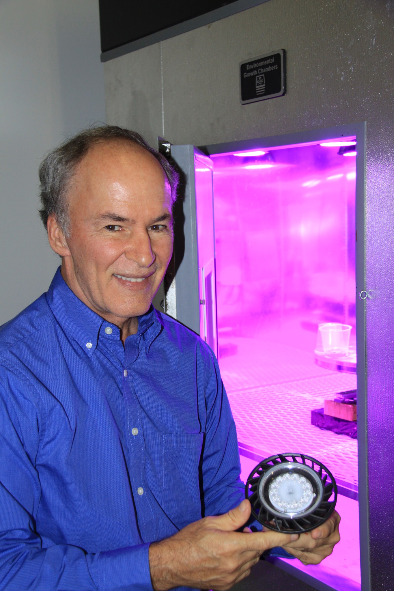 Dr. Ray Wheeler, lead for Advanced Life Support Research activities at Kennedy Space Center, holds a red and blue LED light fixt