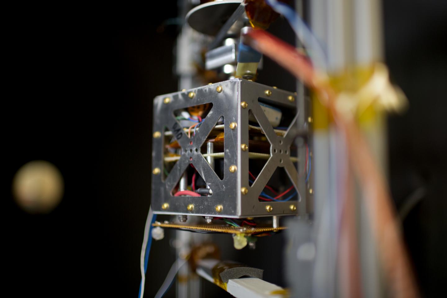 A small satellite levitates in a vacuum chamber used to test thruster design in the Space Propulsion Lab at MIT.