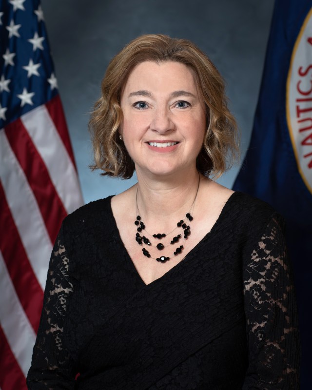 Portrait of Susan Kevdzjia with U.S. and NASA flags in background.