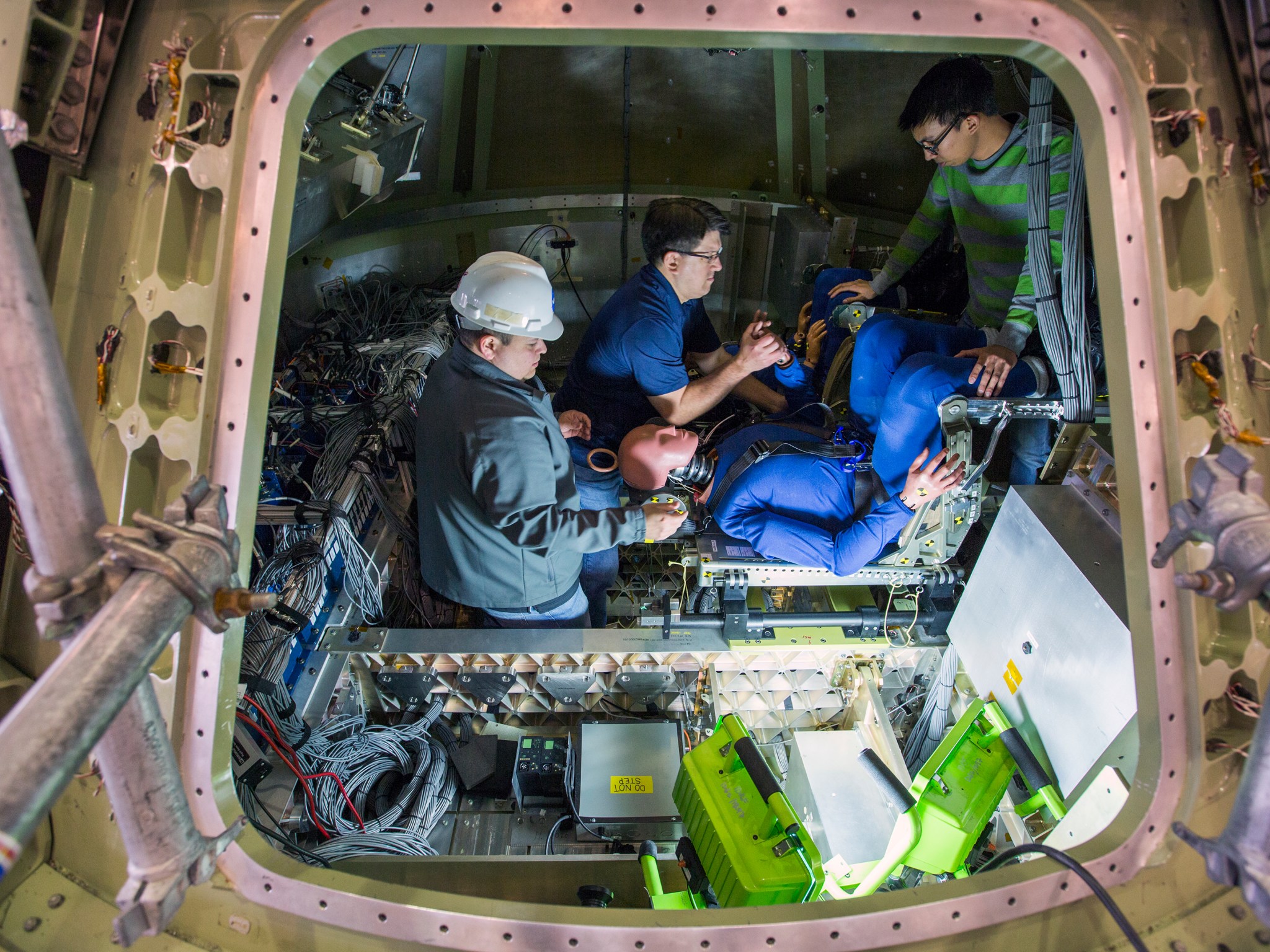 Engineers at NASA’s Langley Research Center install test dummies into the crew suits of an Orion test article.