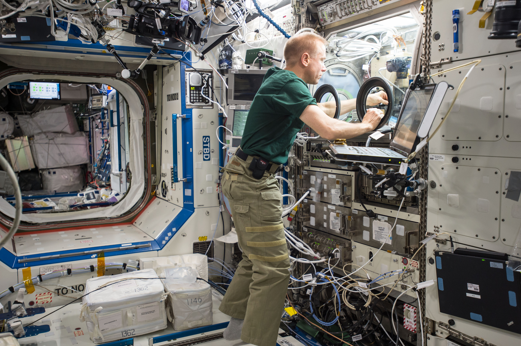 NASA astronaut Tim Kopra sets up hardware for the Burning and Suppression of Solids – Milliken, or BASS-M, experiment.