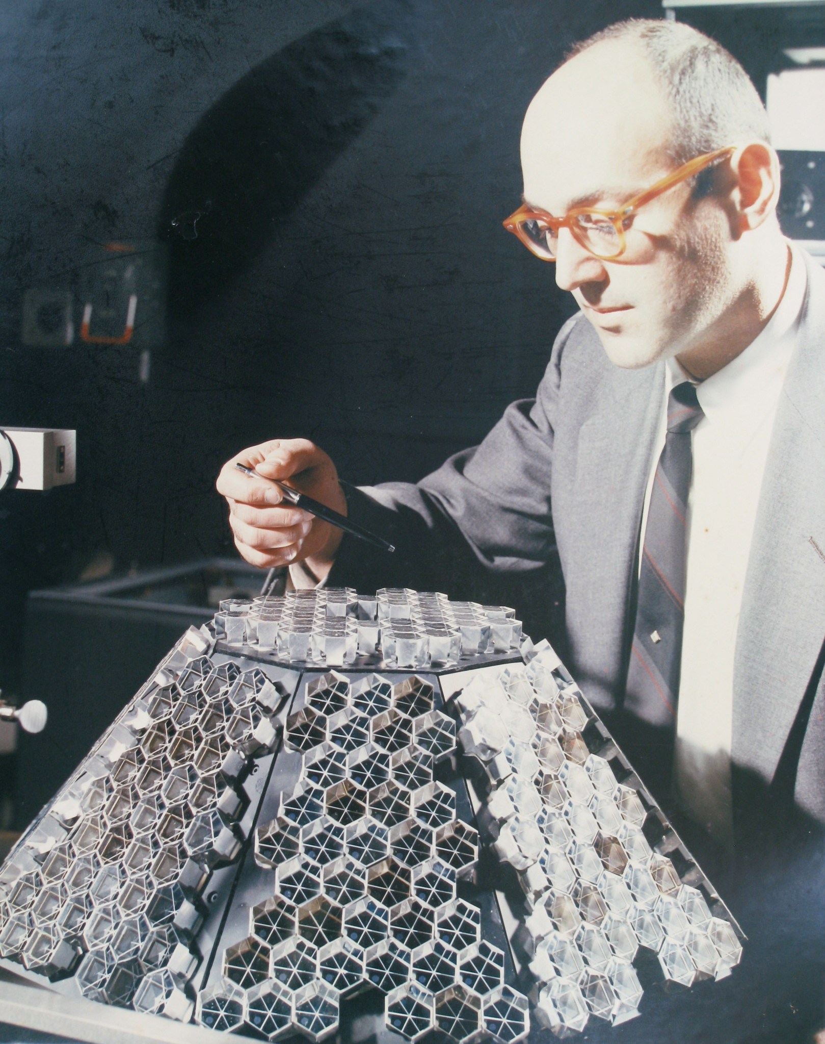 Photo of Goddard physicist Henry Plotkin examining the retroreflector array for Beacon Explorer A before integration onto the 1964 satellite.