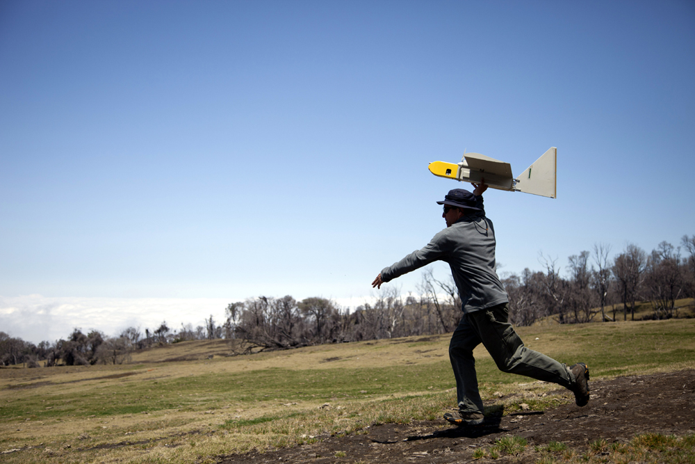 Researcher with unmanned aircraft in hand about to launch it overhead