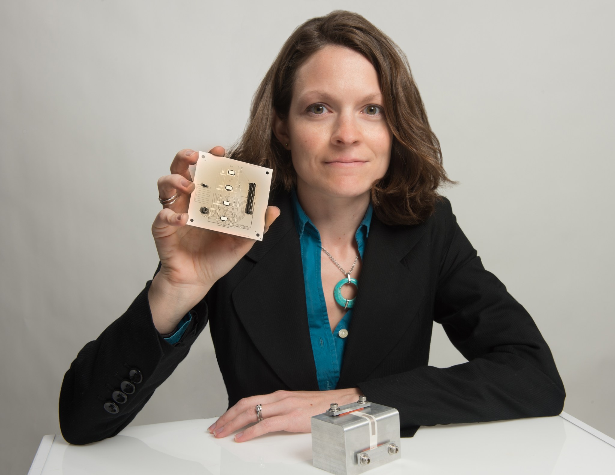 Goddard technologist Beth Paquette holds a 3-inch-by-3-inch ceramic board.