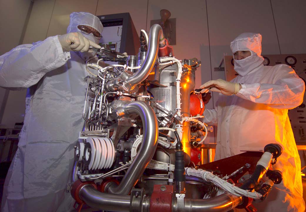 Technicians verify proper clearance and secure cable bundles on a completed propulsion engine.