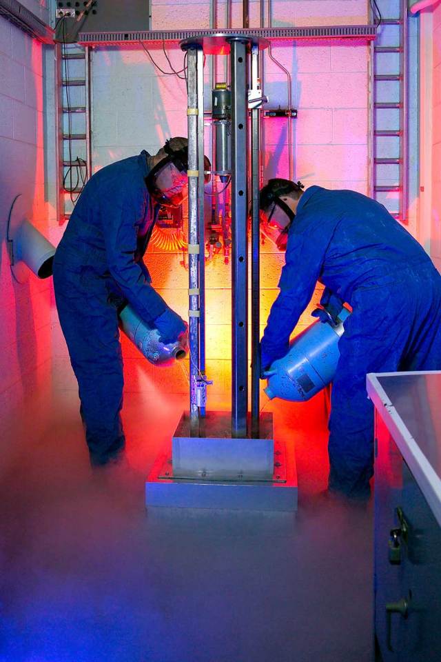 Technicians prepare a sample exposed to liquid oxygen (LOX) for mechanical impact testing.