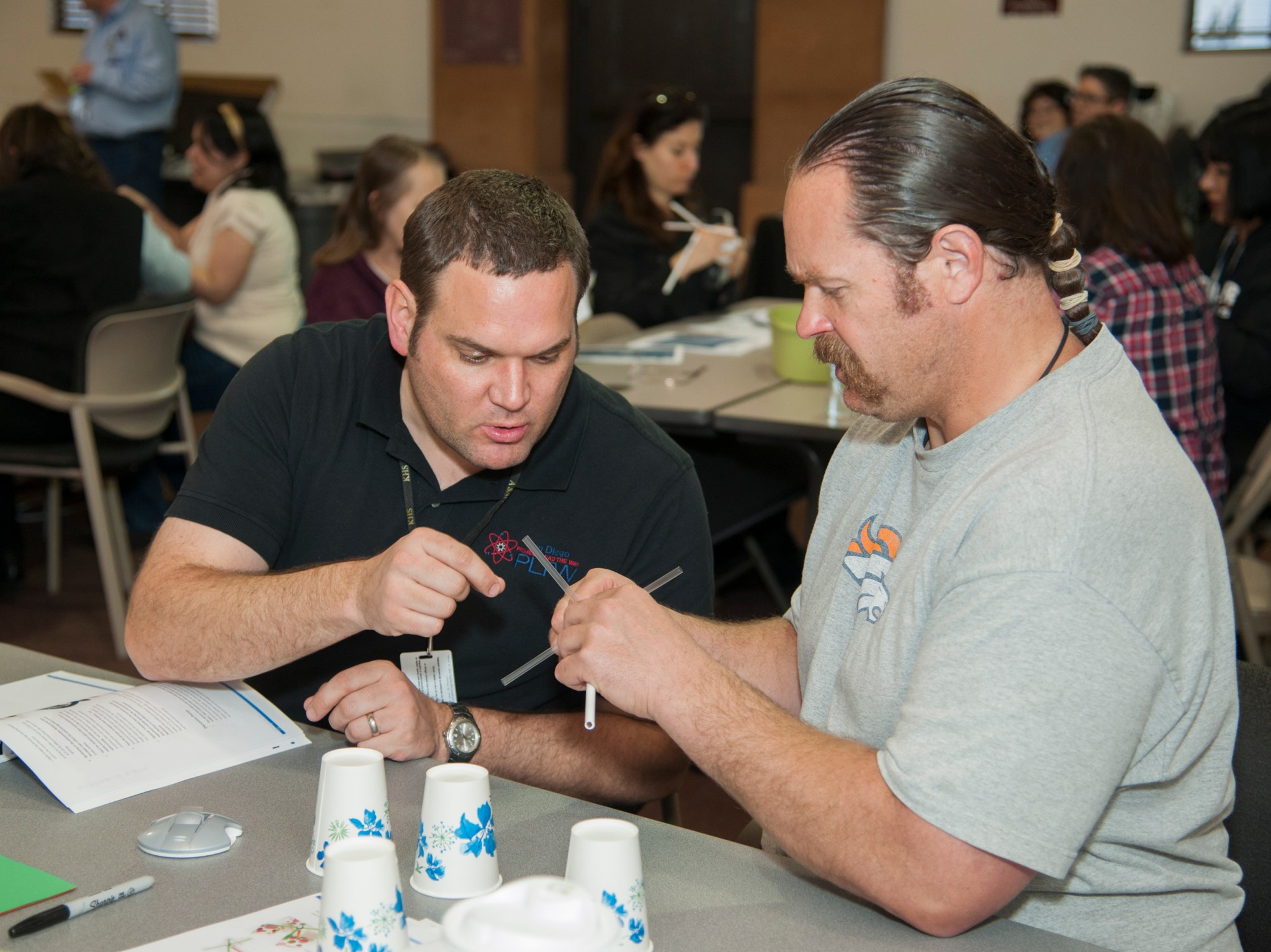 Local teachers building an anemometer, which measures wind speed, using a straw spindle and pencil so it can freely spin.  