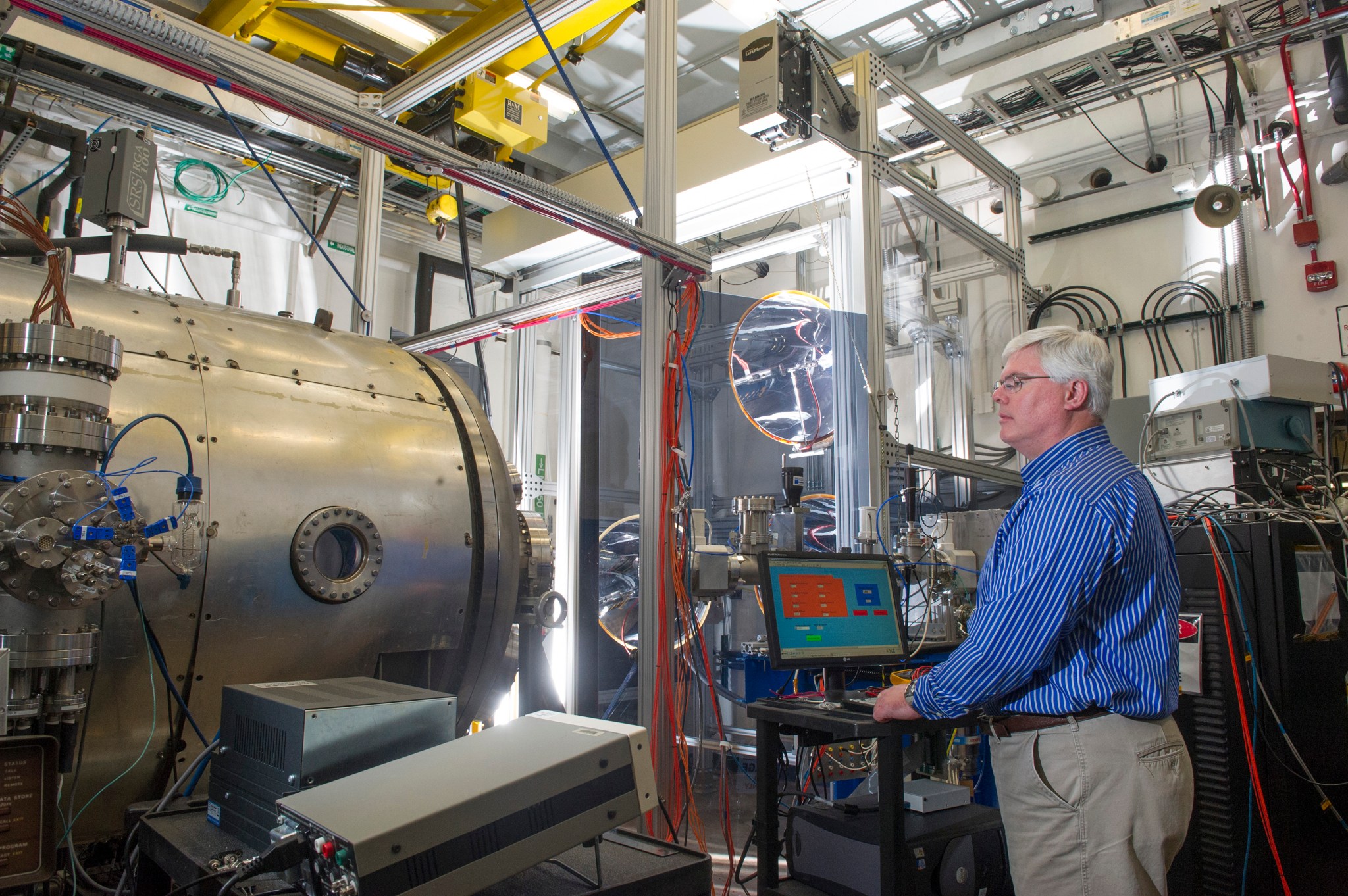 Todd Schneider adjusts the light hitting a sample inside the High Intensity Solar Environment Test system chamber.