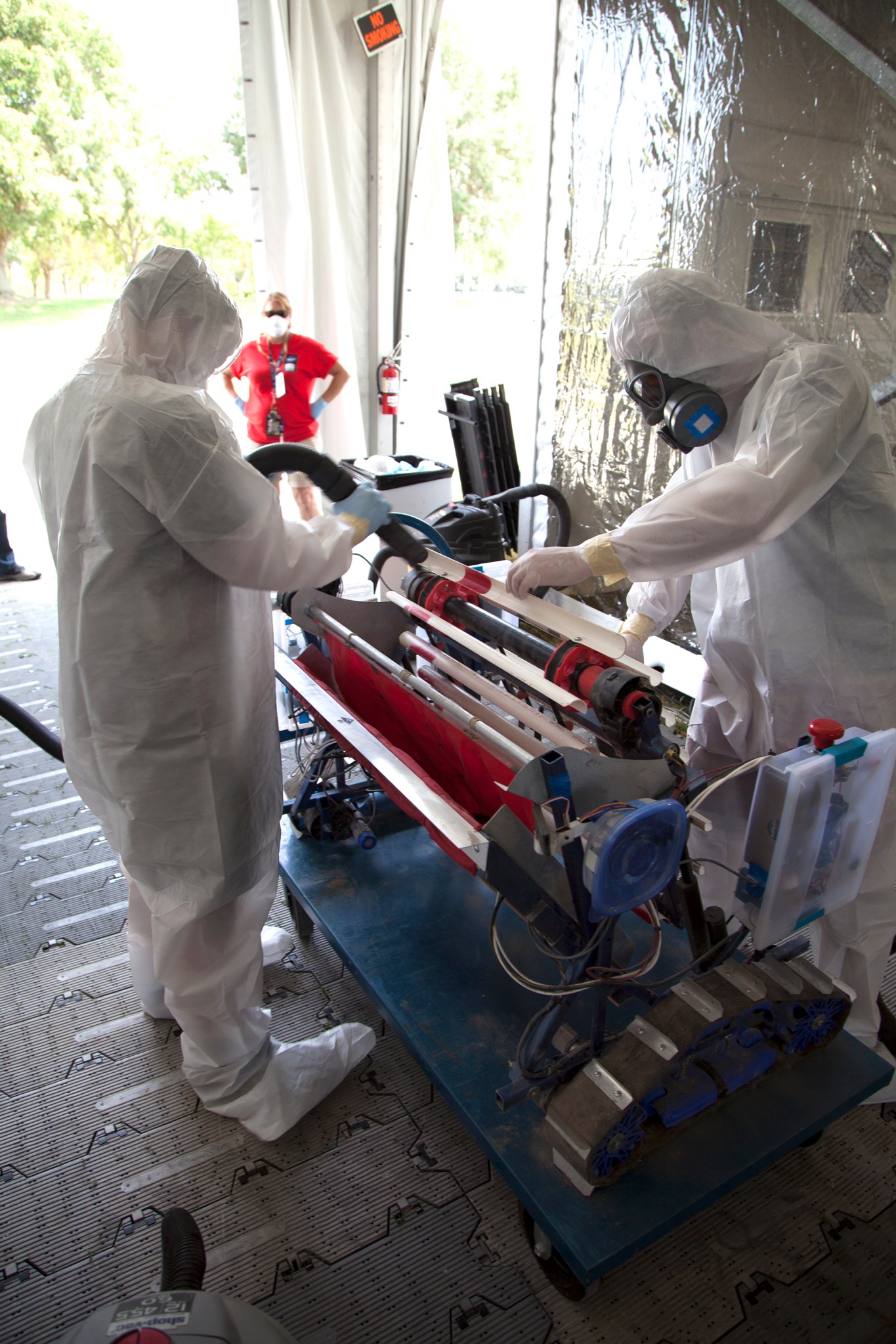 Participants clean their robotic excavator following a practice round in the regolith bin.