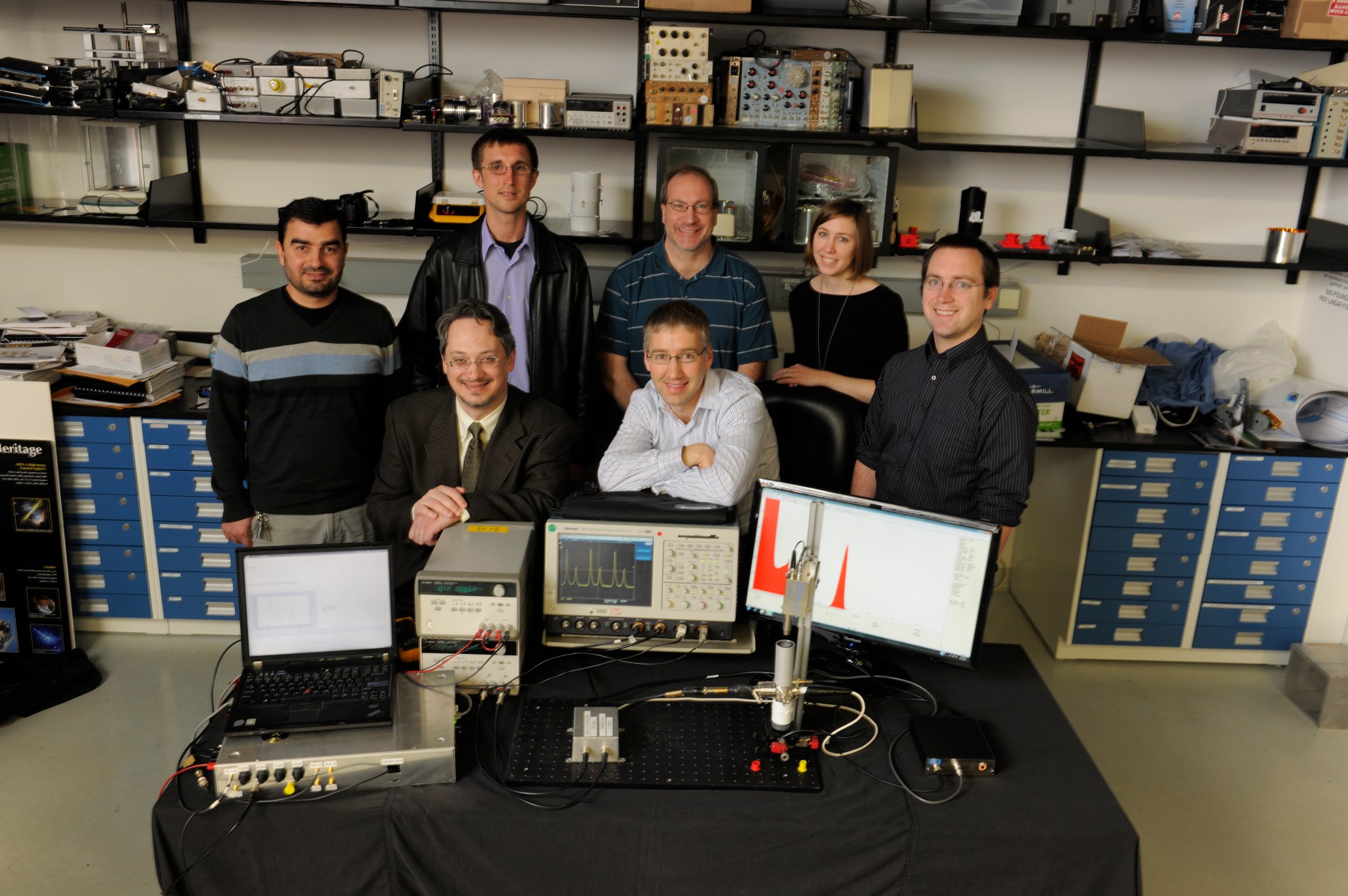 Technologists in lab pose for photo with computer displays.