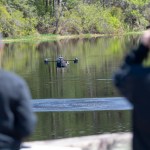 Drone people pilot a drone flying low over a body of water