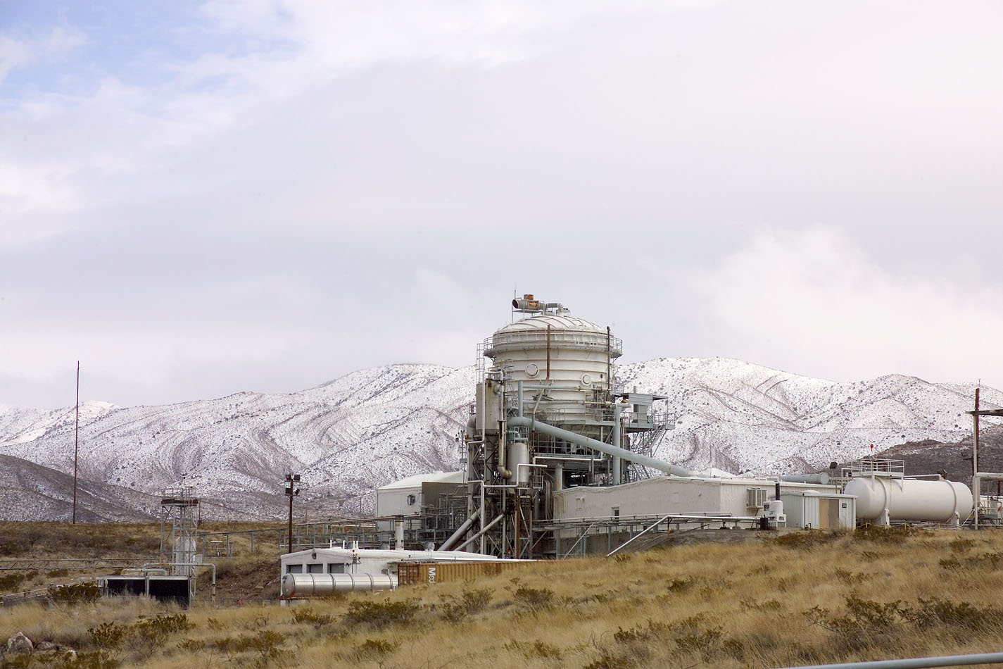 A vacuum test stand with a rare snow fall in the foothills behind the Propulsion Test Area.