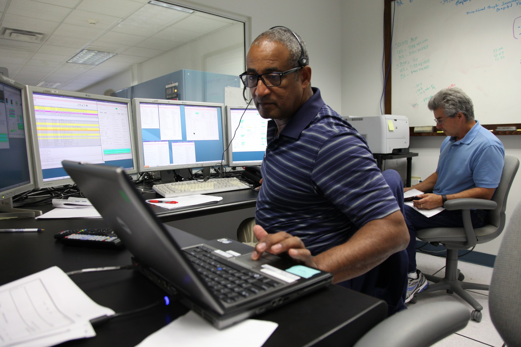 Photo of employees performing interface testing for the OSIRIS-REx spacecraft inside the PHSF.