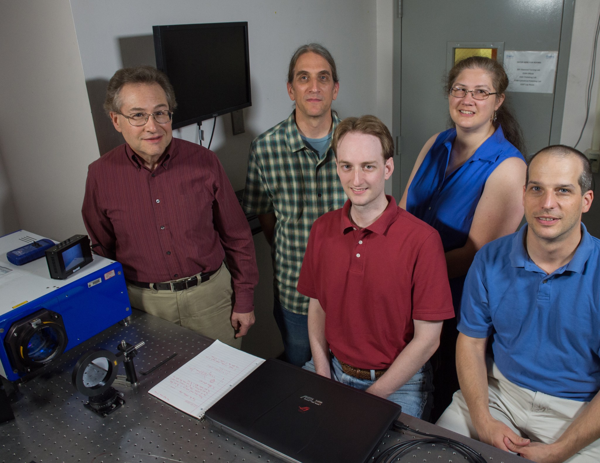 Five people stand together, looking at the camera. A blue rectangular box, the photon sieve, sits on a table in front of them.