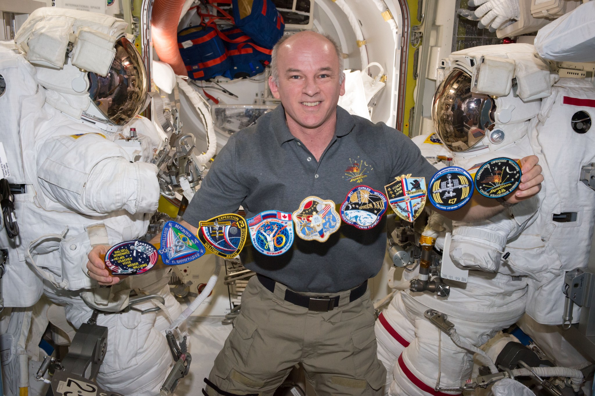 NASA astronaut Jeff Williams poses on the International Space Station with patches for the missions he has participated in.