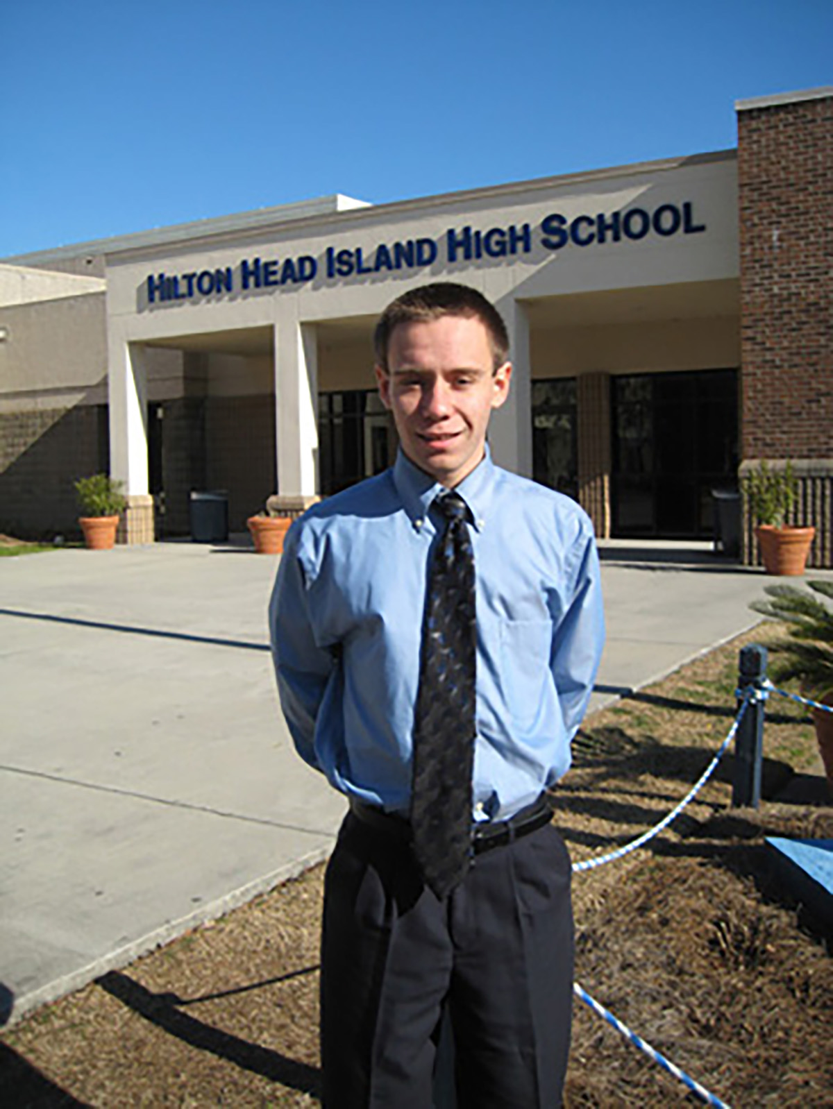 Male student standing in front of his school.