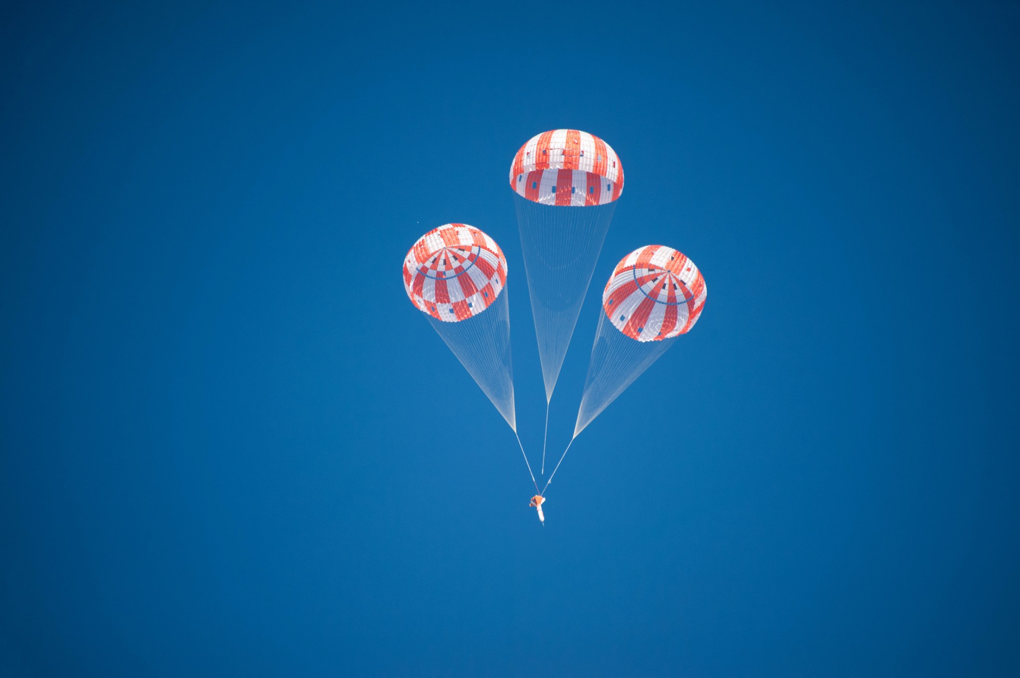 An Orion test article descends under three main parachutes