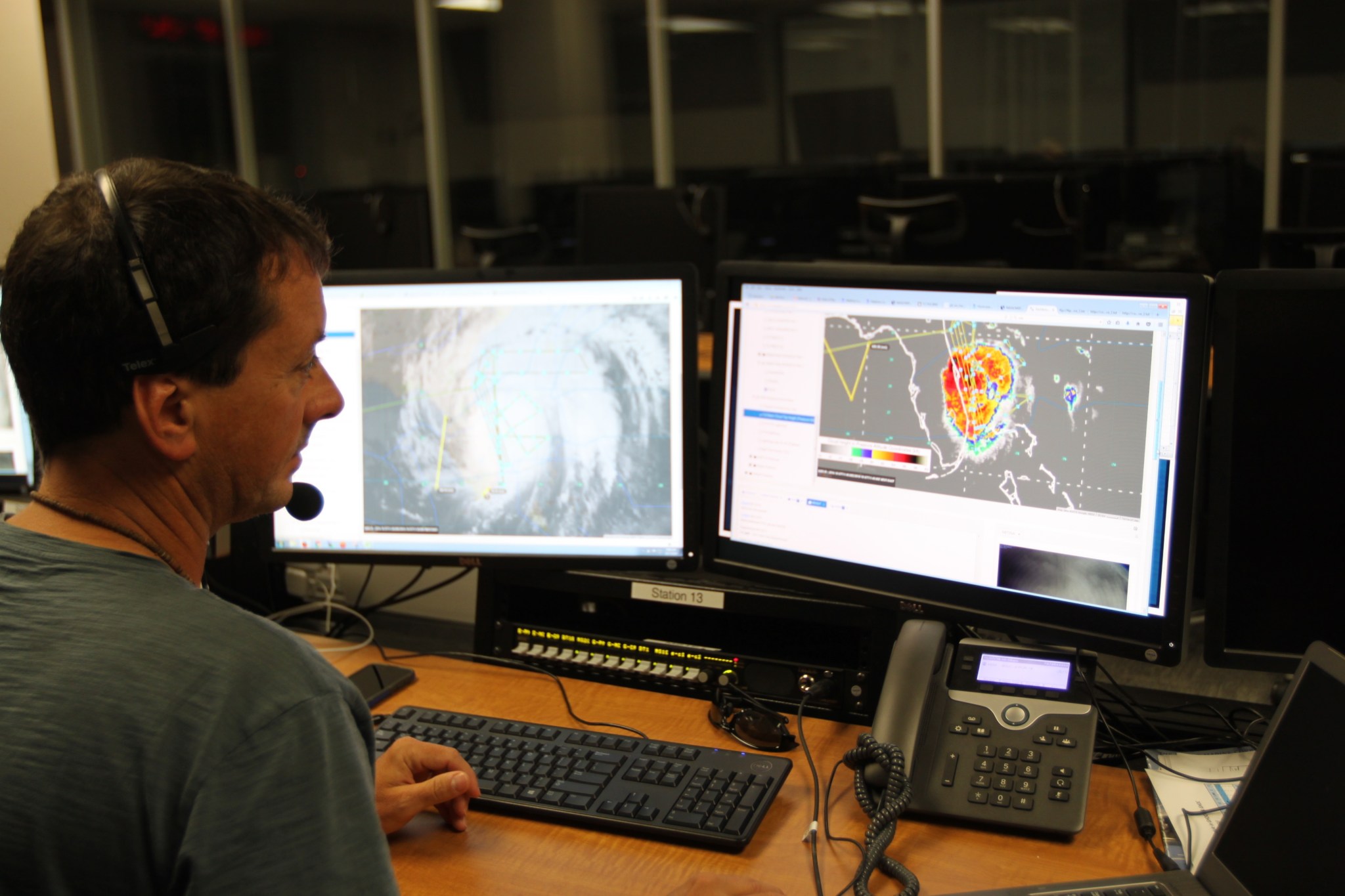 Jason Dunion looks at two computer screens, each showing a different satellite image of Matthew.