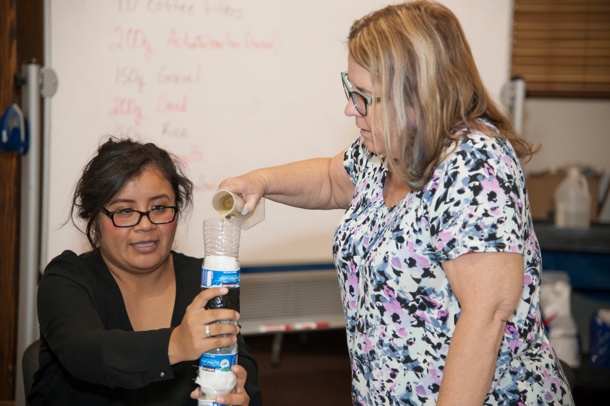 Educators pour water into their handmade water filtration system.