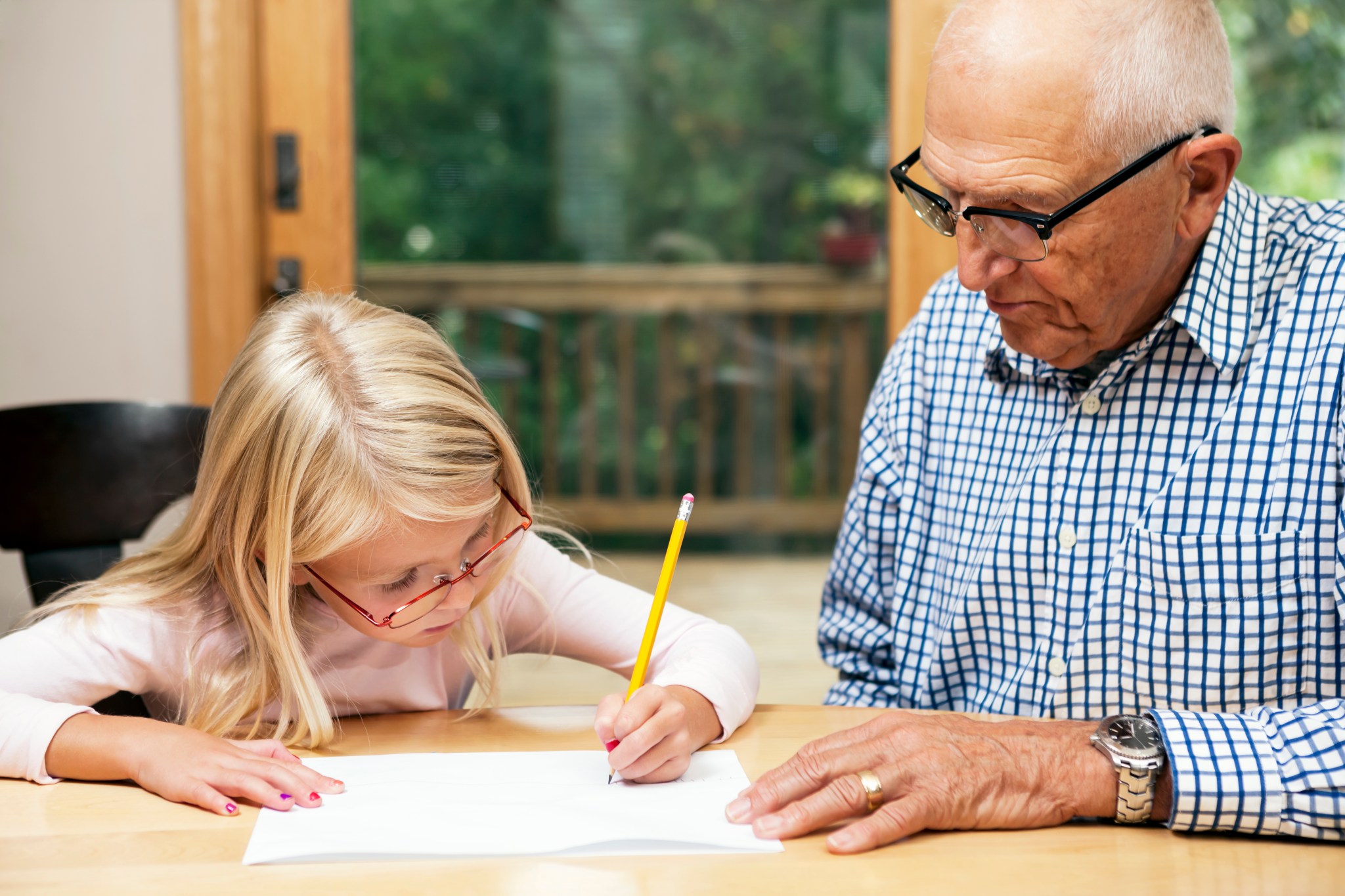 Grandfather working with grand daughter on homework.