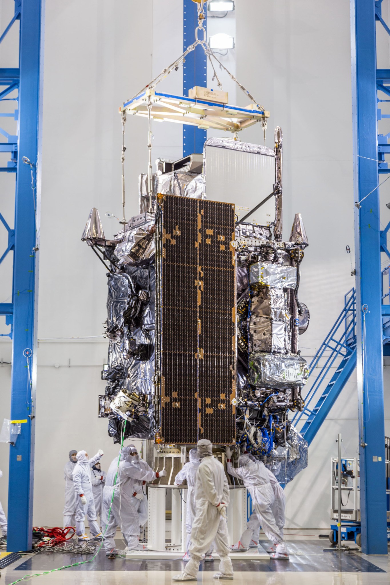 men in paper suits surround satellite in cleanroom