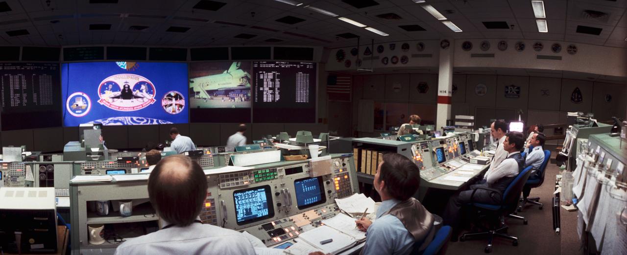Mission Control Center watching STS-41B post-landing activities. The mission patch is displayed on one of the screens.