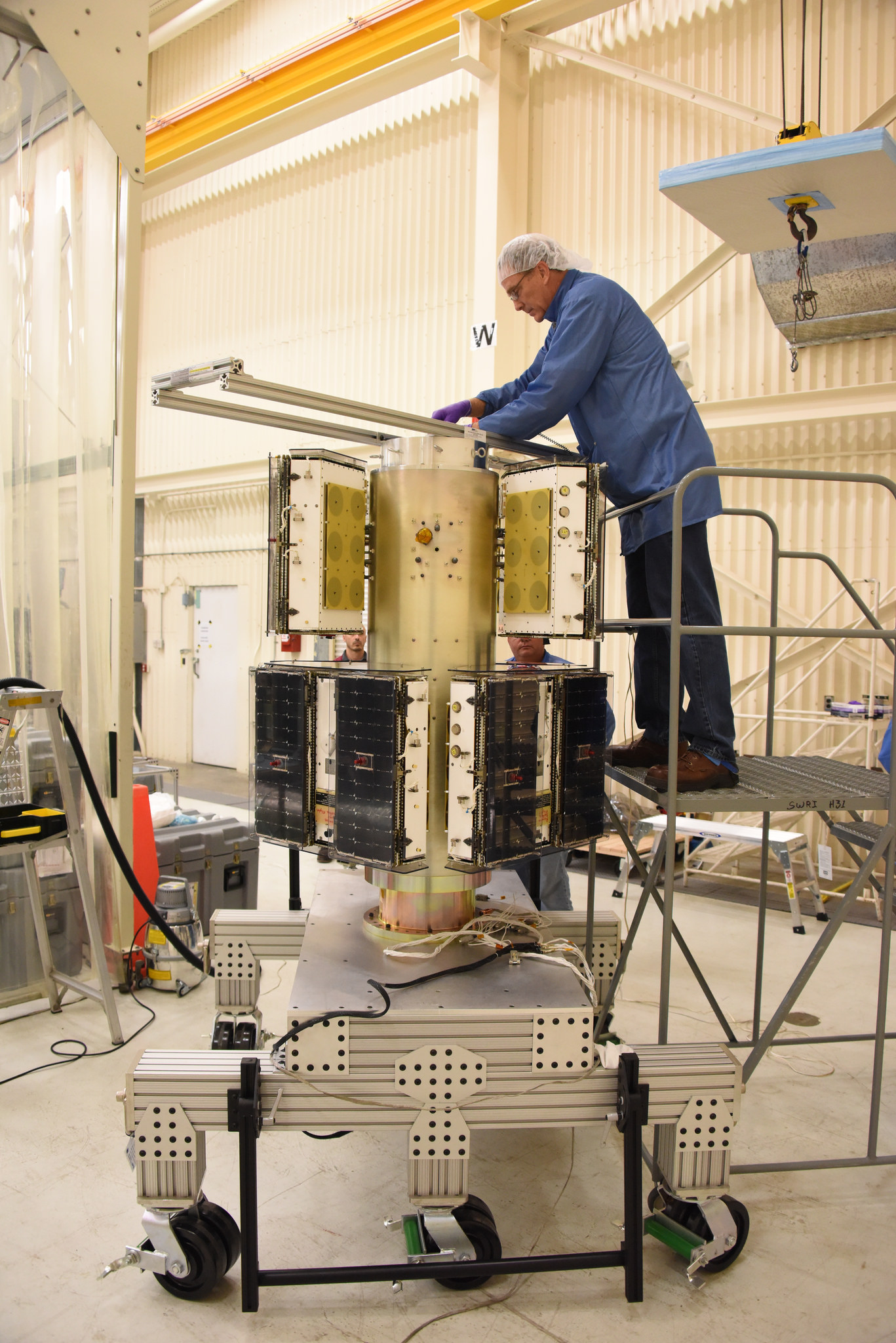 An Orbital ATK technician checks the installation of two of the eight the CYGNSS microsatellites on their deployment module