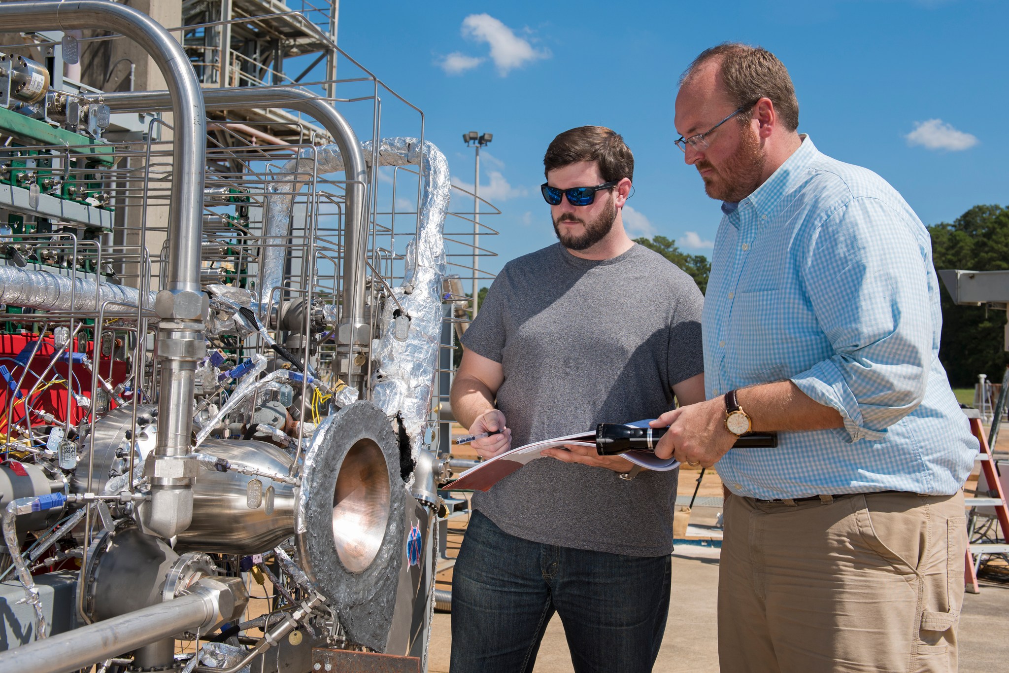 Graham Nelson, right, and Andrew Hanks examine a combustion chamber for an additively manufactured breadboard engine project.