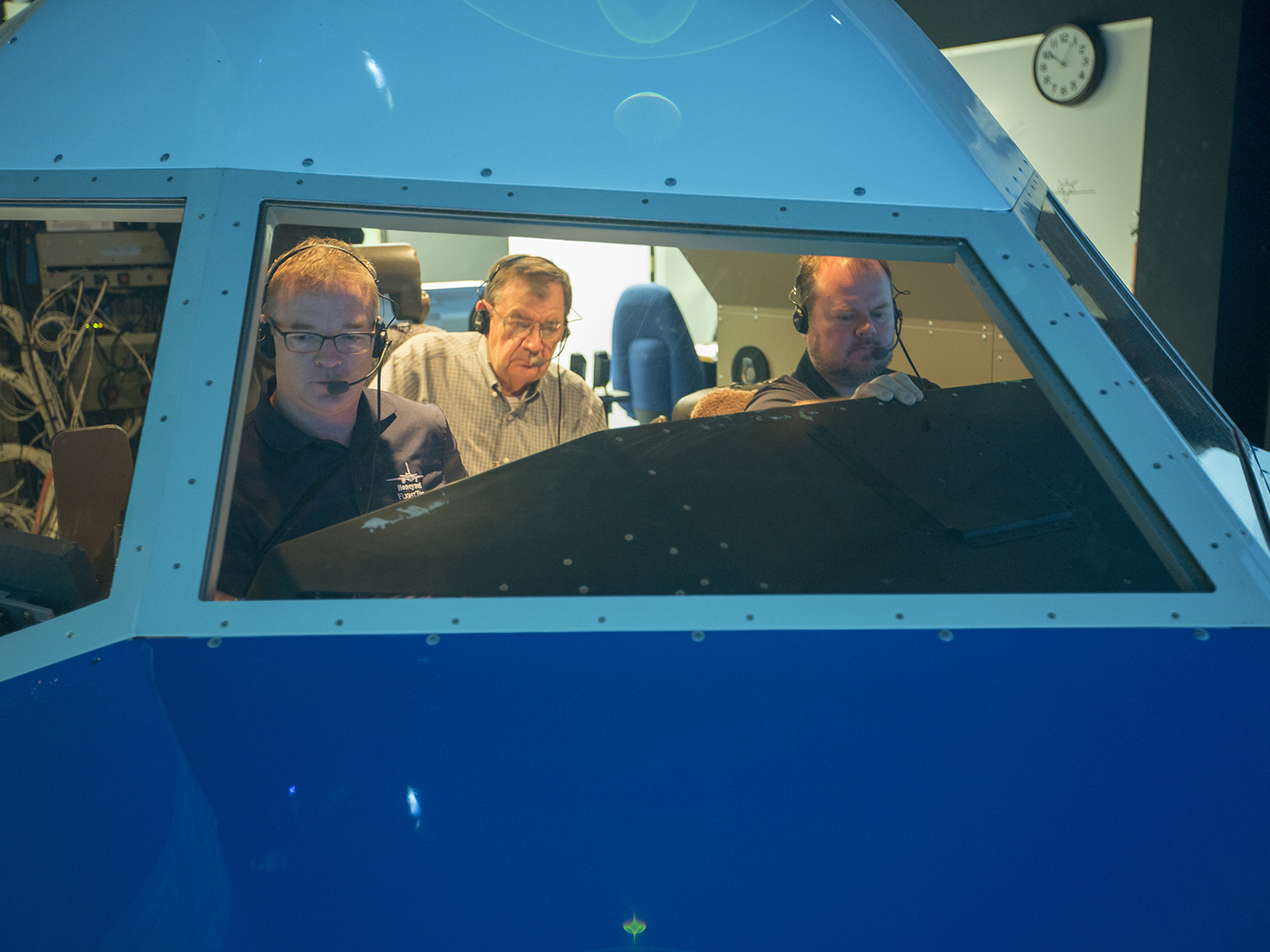 Three men inside a cockpit.