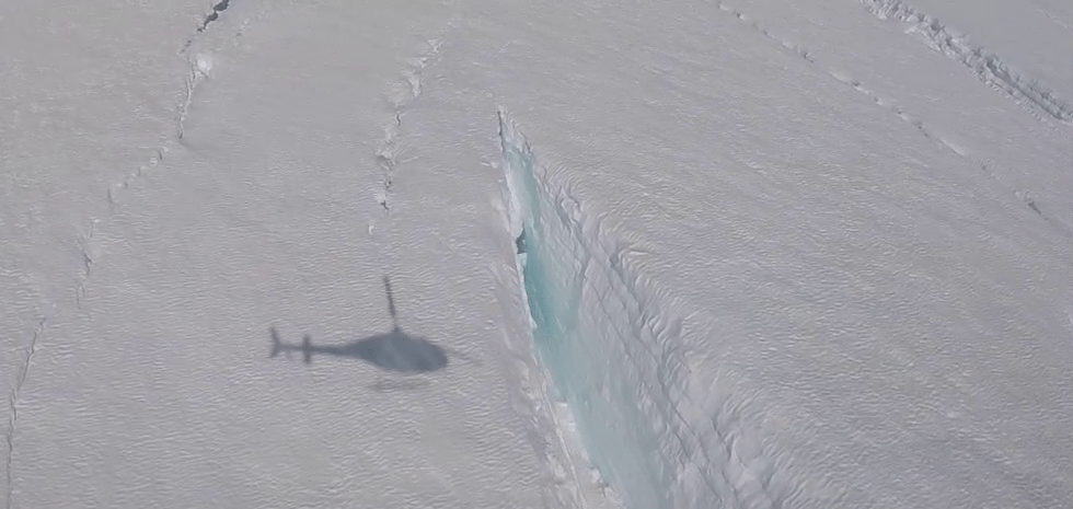 shadow of helicopter near a crevasse in ice