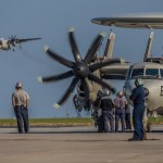 Technicians stand around an E-2 Navy aircraft.