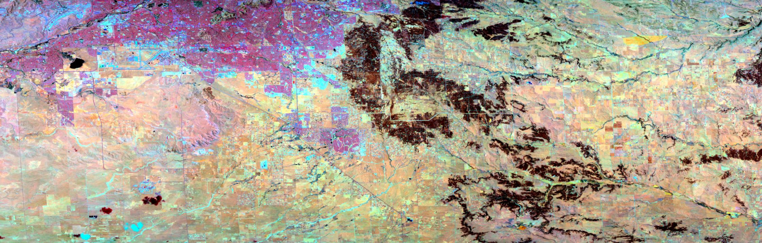 A false-color satellite image looks down at a section of ground that is a patchwork of rectangles. The top left corner is mostly a bright magenta,