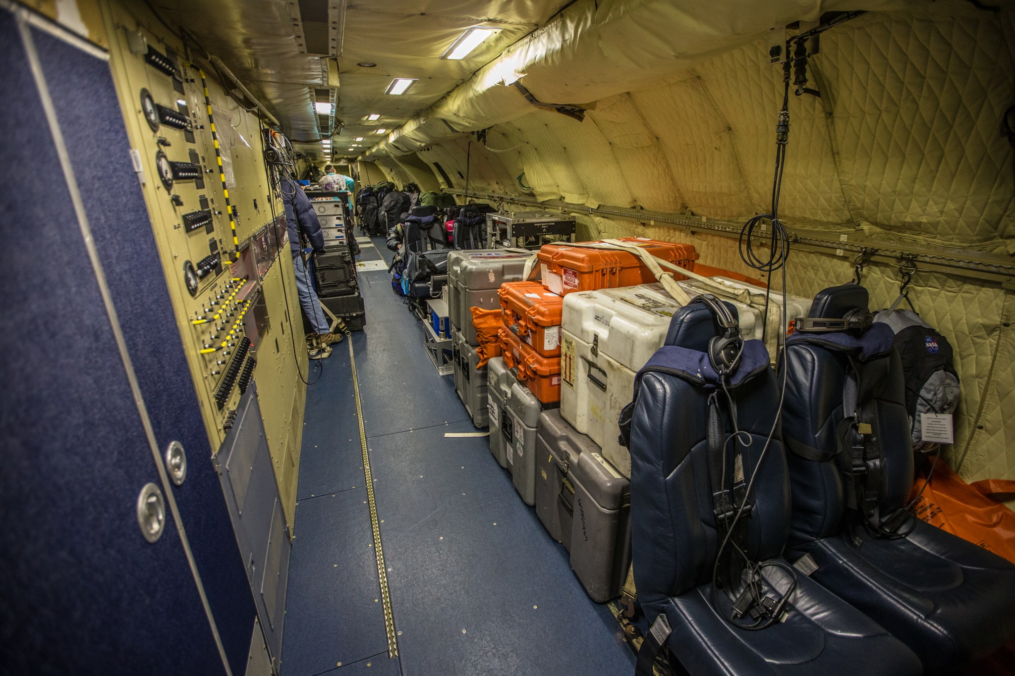 Inside the P-3 plane showing a row of cargo on one side and equipment racks on the other.