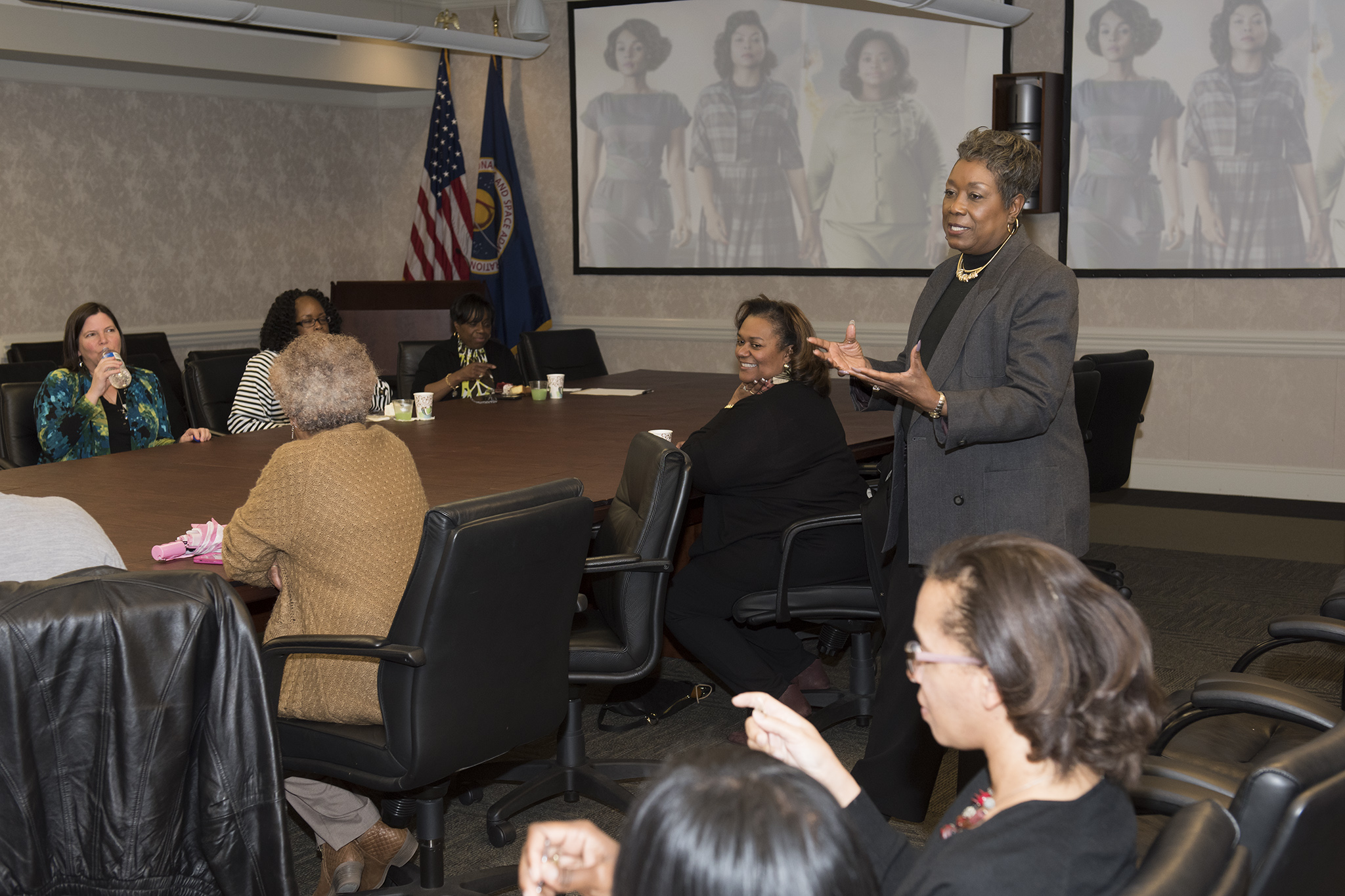 Diane Cain, standing near center, speaks to an audience gathered for an agency-wide Livestream presentation by author Margot Lee