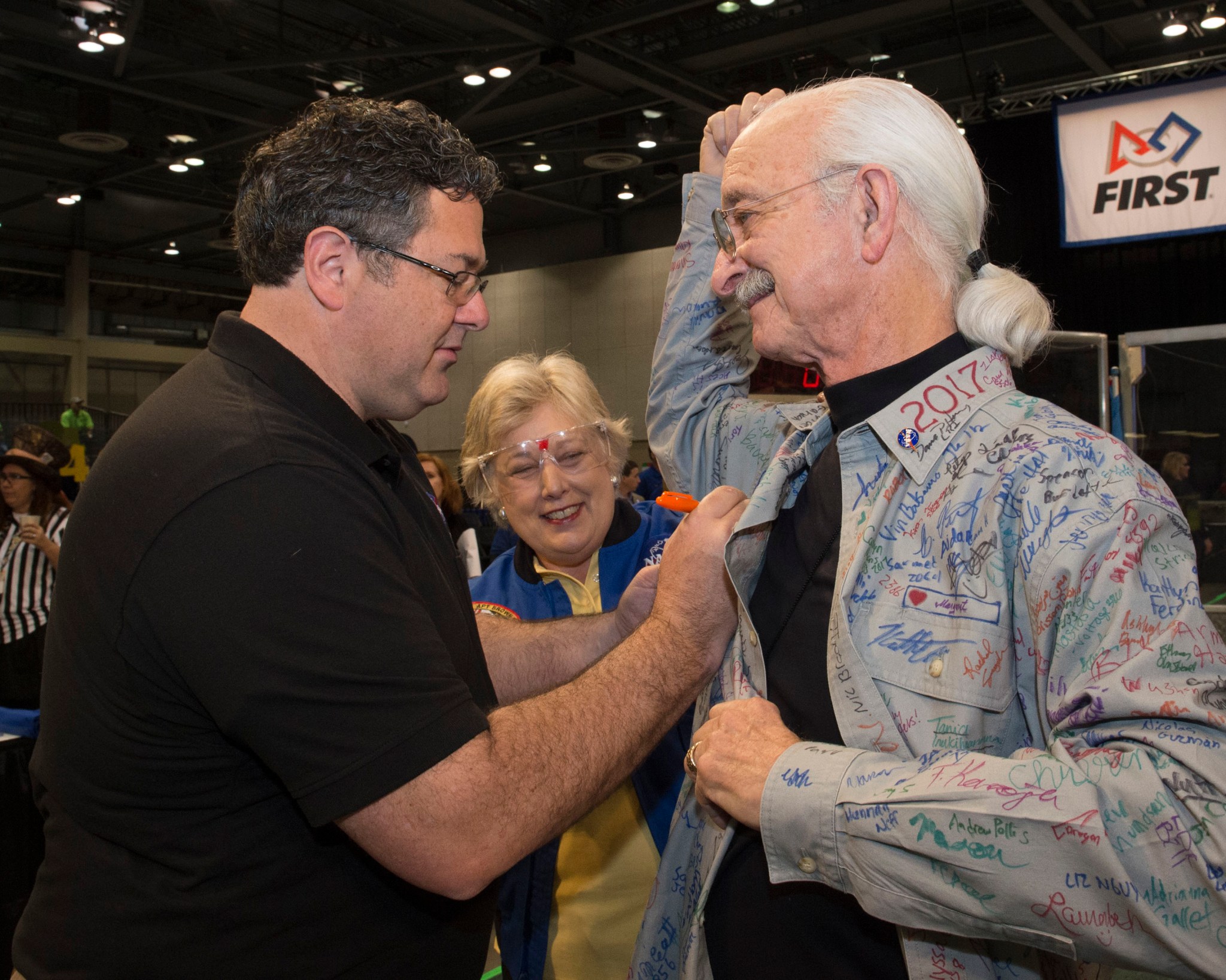 Marshall Director Todd May, left, adds his signature on Woodie Flowers' shirt as former astronaut Jan Davis, center, looks on. 