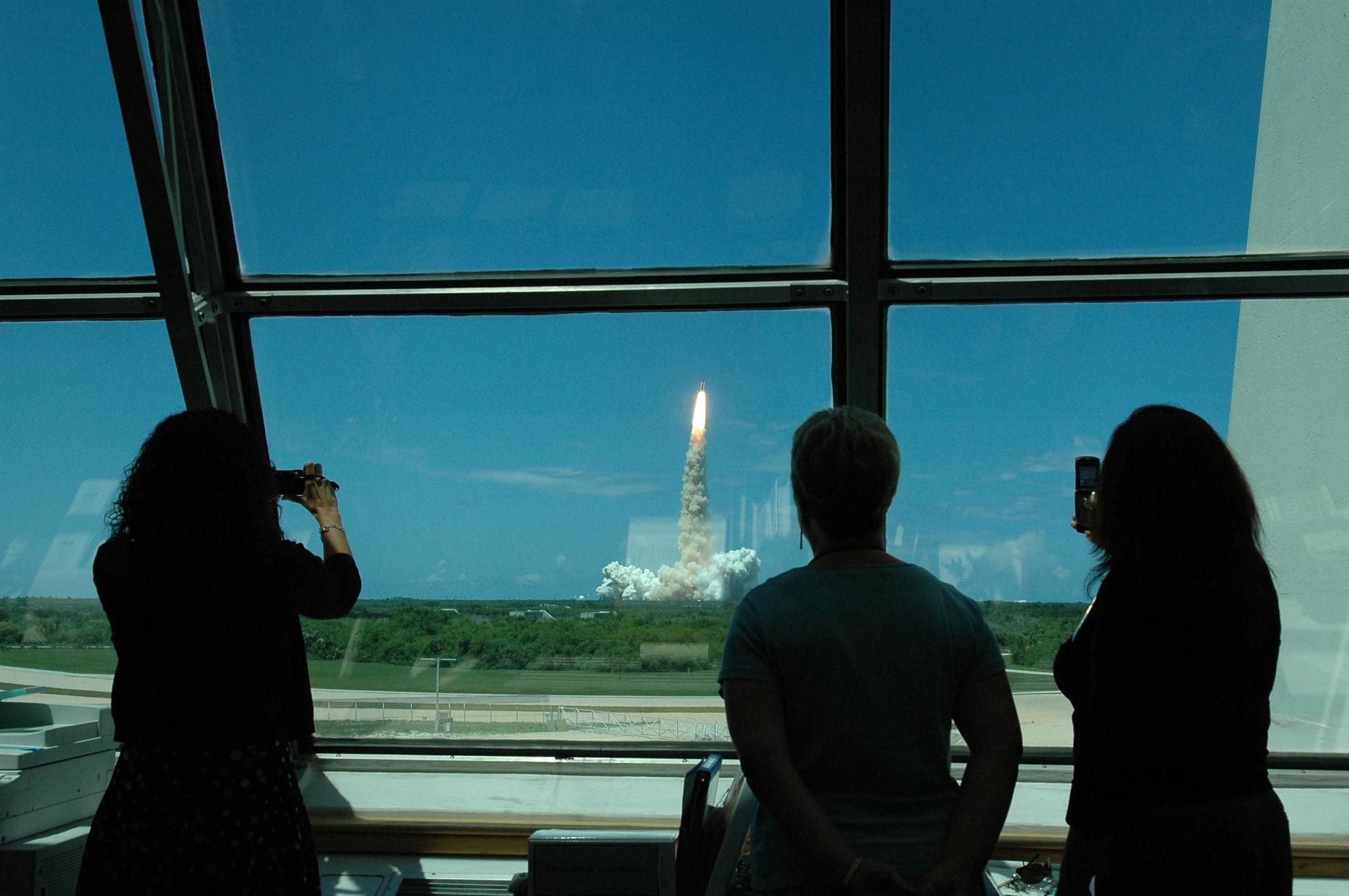 Workers in Firing Room 4 of the Launch Control Center take advantage of the view as space shuttle Discovery lifts off on mission