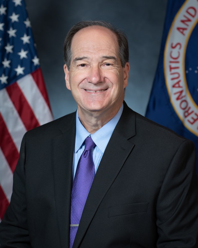 Portrait of Scott Graham with U.S. and NASA flags in the background.