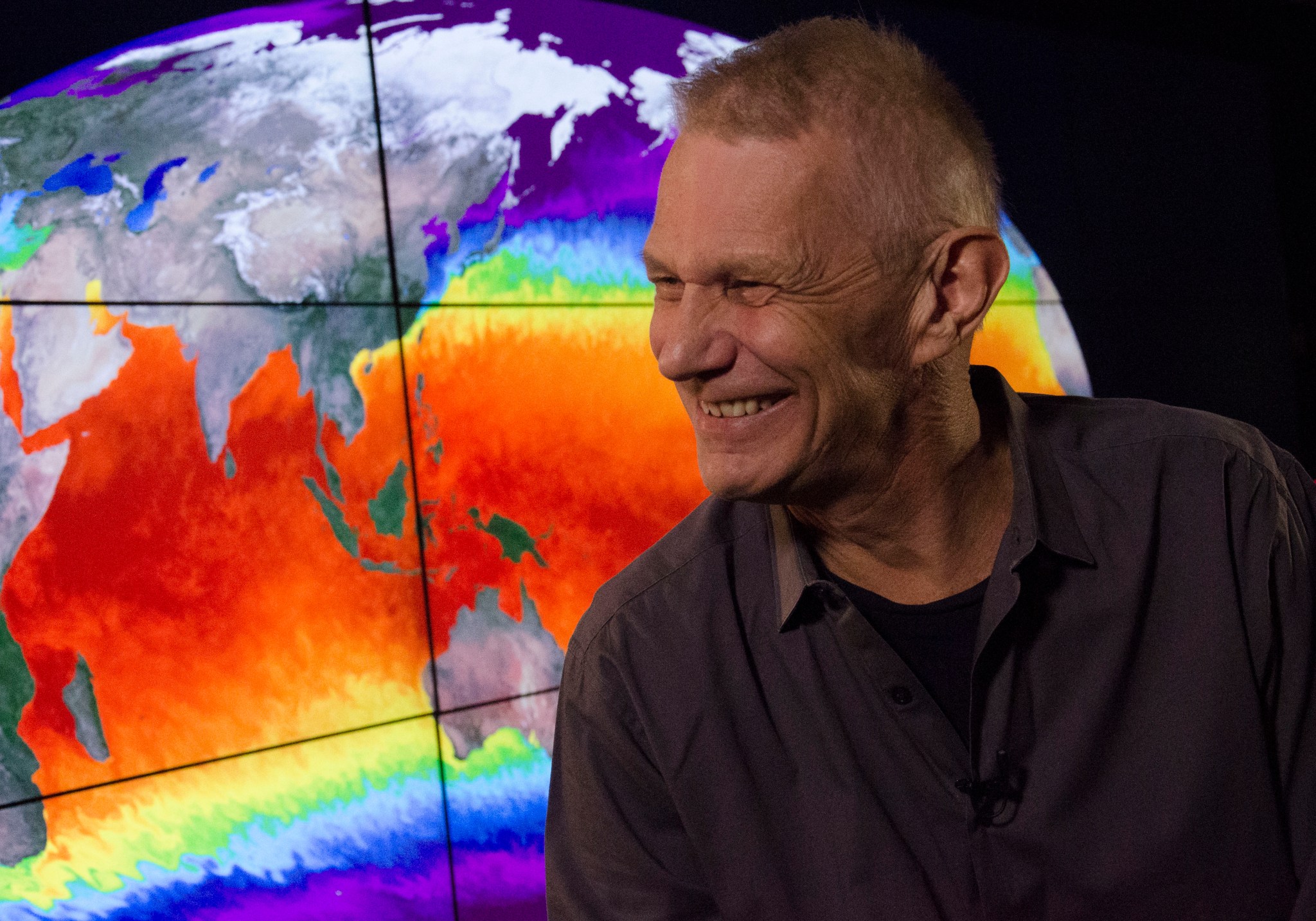 Piers Sellers, smiling, in front of a computer monitor displaying a map of Earth