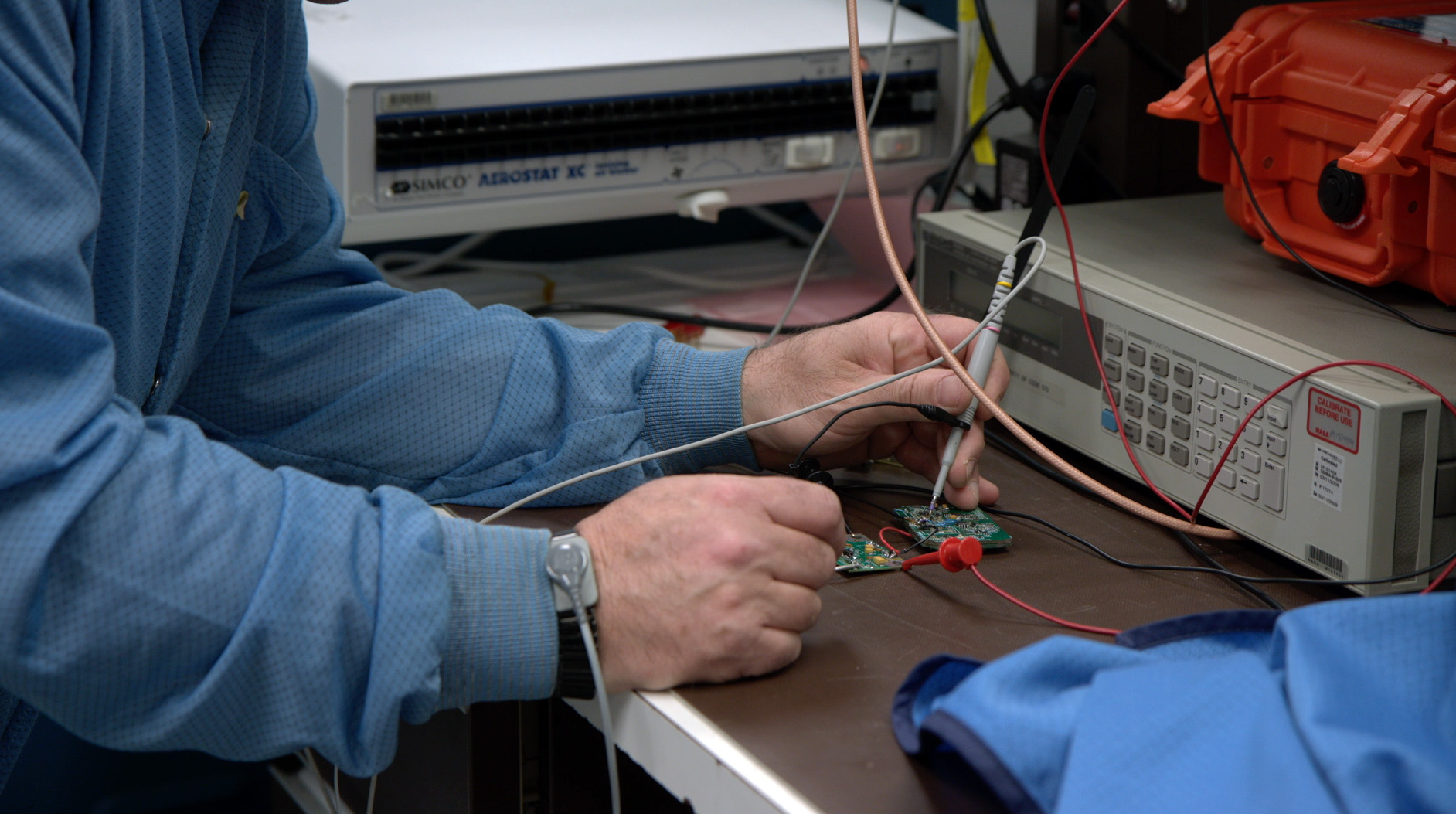 A technician works on a prototype of a second-generation emergency locator beacon, which will improve search-and-rescue efforts.