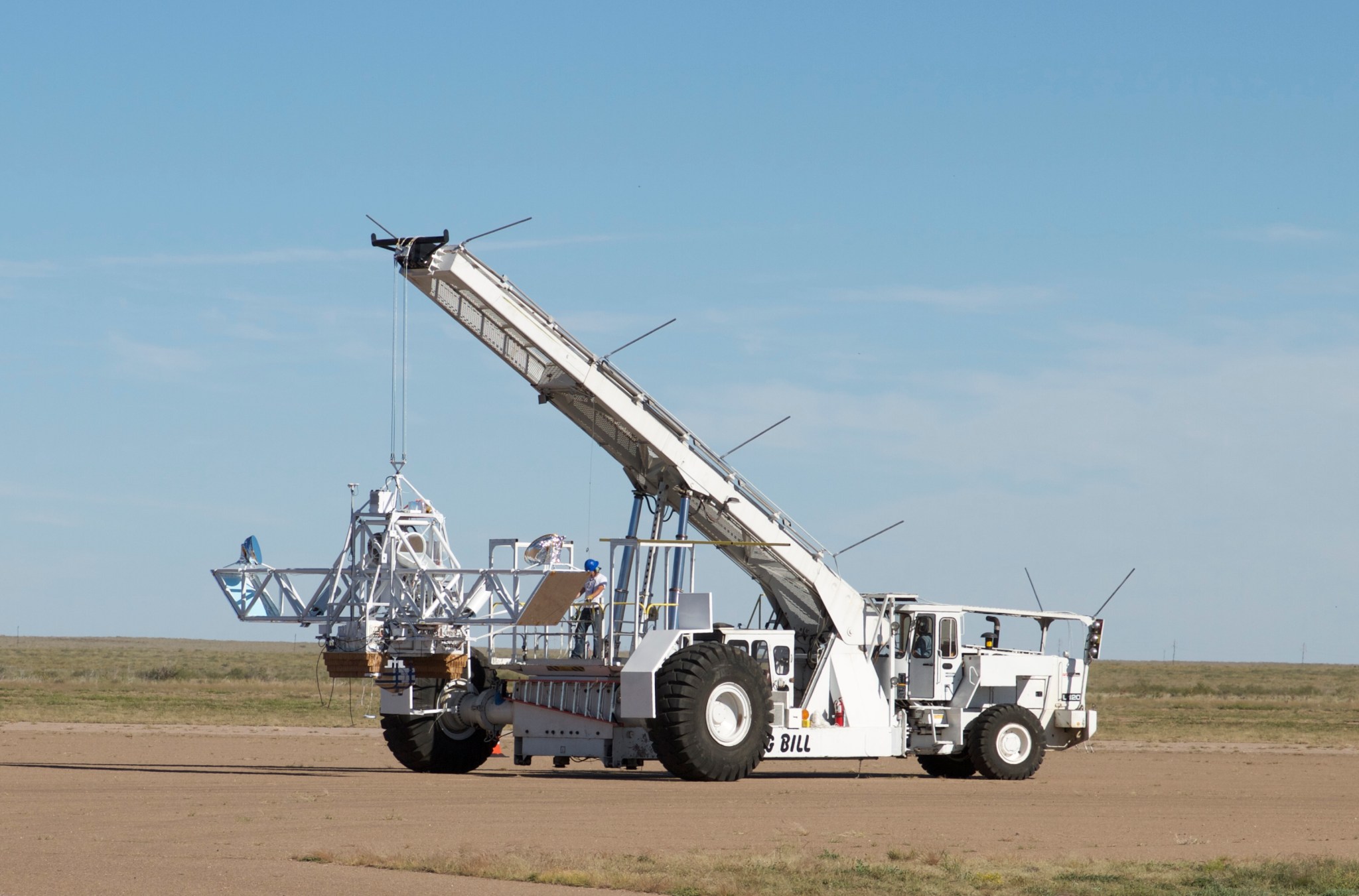 The BETTII payload is held up by a crane as it's driven across a dusty landscape.