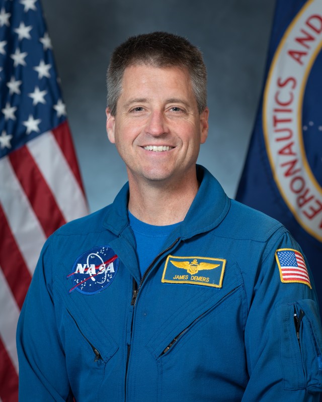 Portrait of James Demer with U.S. and NASA flags in background.